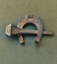 Anstecknadel in Form eines Hufeisen und Hufnagels