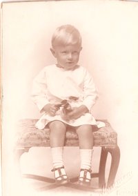 Foto kleines Kind sitzend auf einer kleinen Bank.