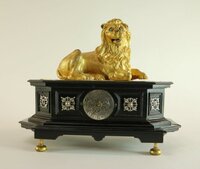 Automaten- Tischuhr mit liegendem Löwen auf profiliertem Ebenholzsockel