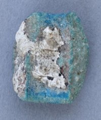 Fragment einer türkisen Glasperle mit seitlichen Rillen