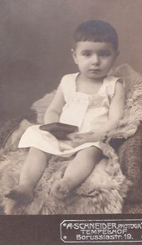 Foto Kind mit Büchlein auf einem Fell